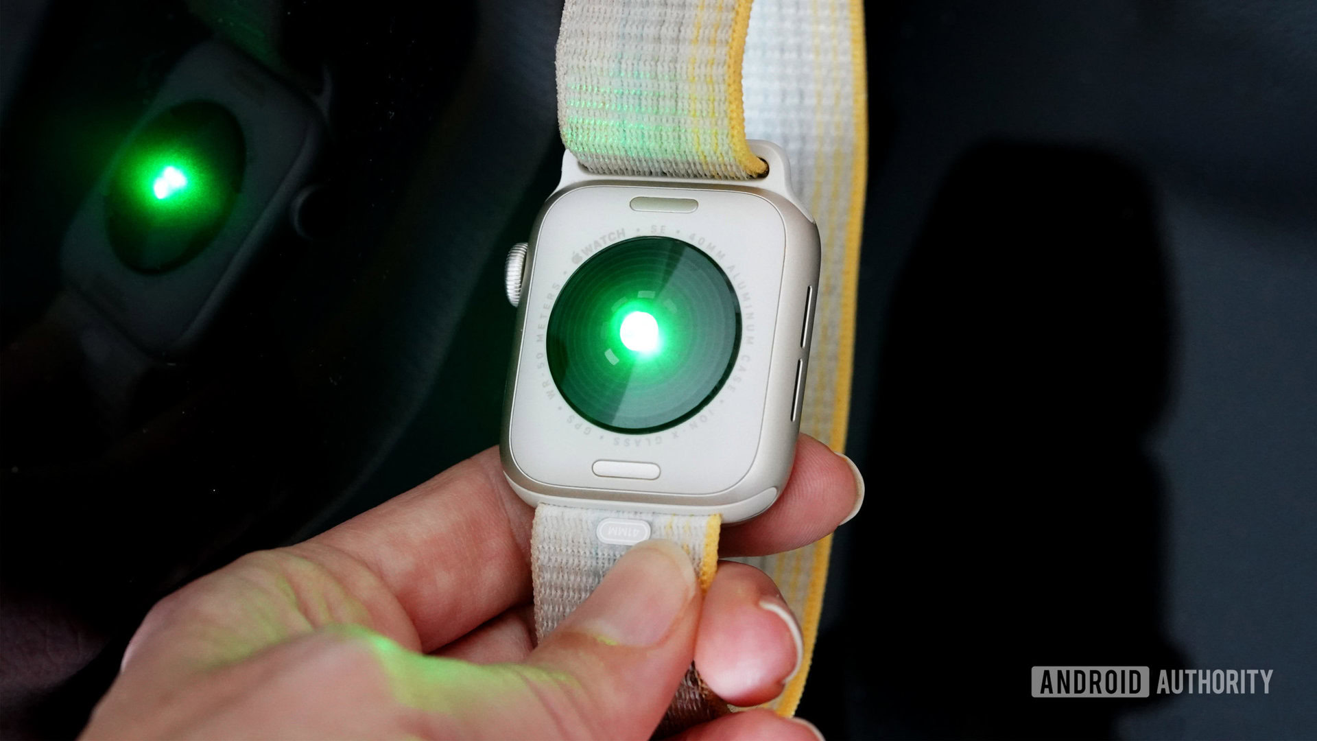 Apple Watch SE 2 Green Light An Apple Watch SE 2 holds the device face down, displaying the heart rate LED lights.