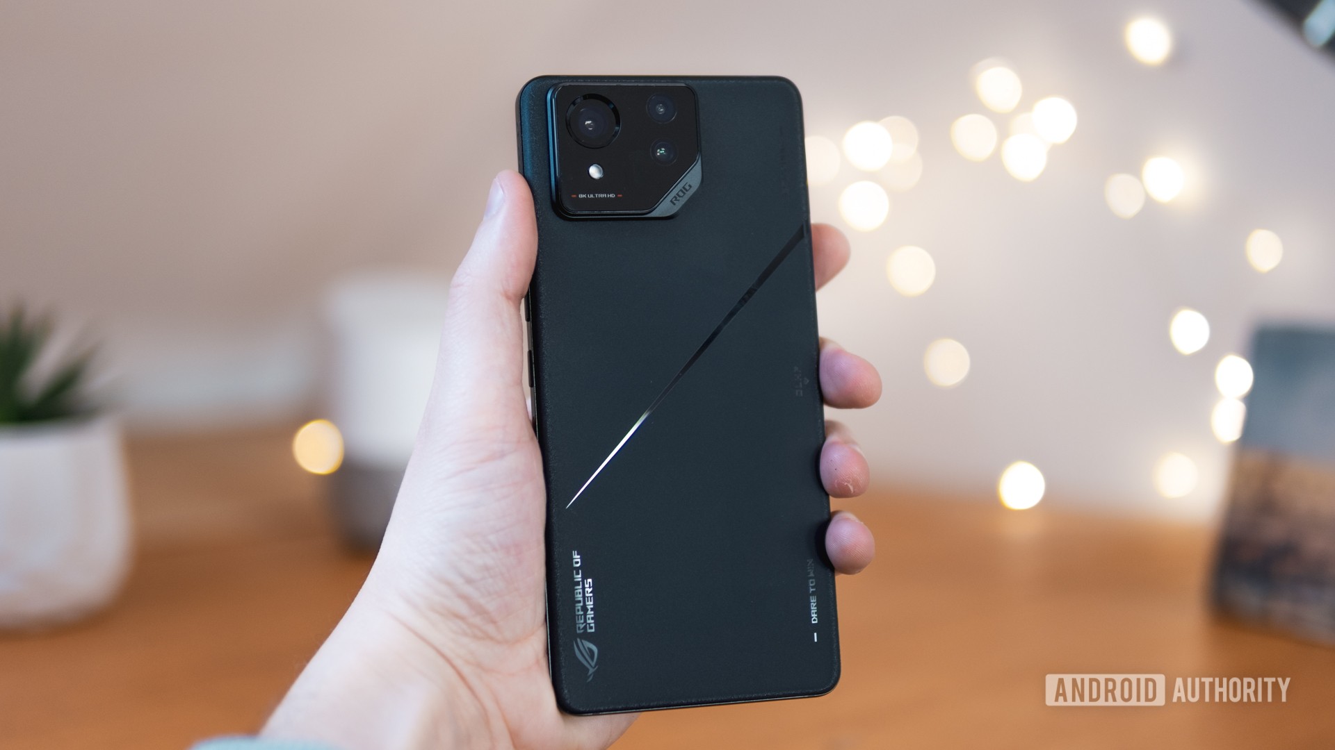 ASUS ROG Phone 8 back in hand with lights in background ASUS ROG Phone 8 back in hand with lights in background