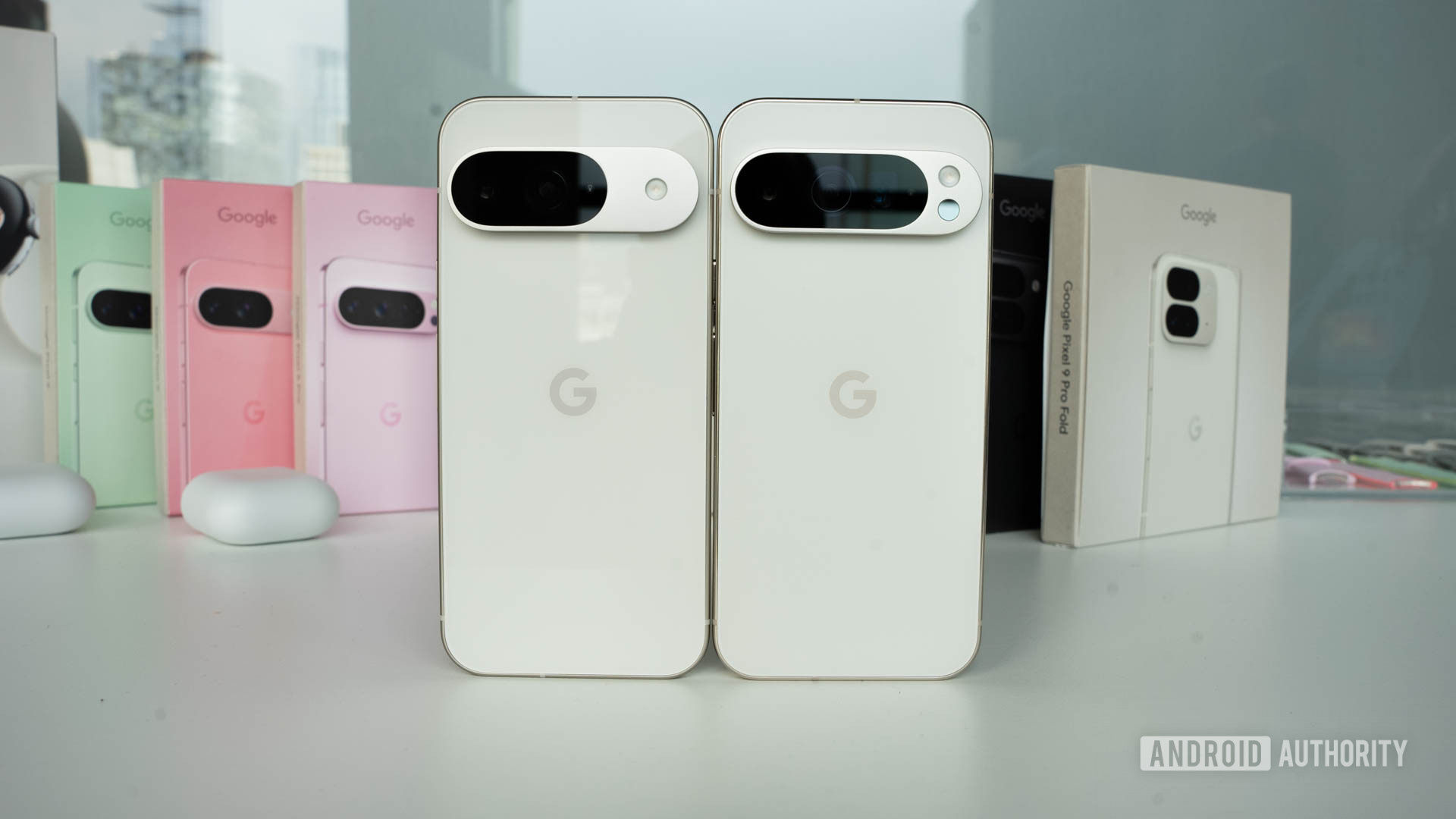 Google Pixel 9 in Porcelain standing next to Google Pixel 9 Pro in Porcelain with retail boxes in background Google Pixel 9 in Porcelain standing next to Google Pixel 9 Pro in Porcelain with retail boxes in background