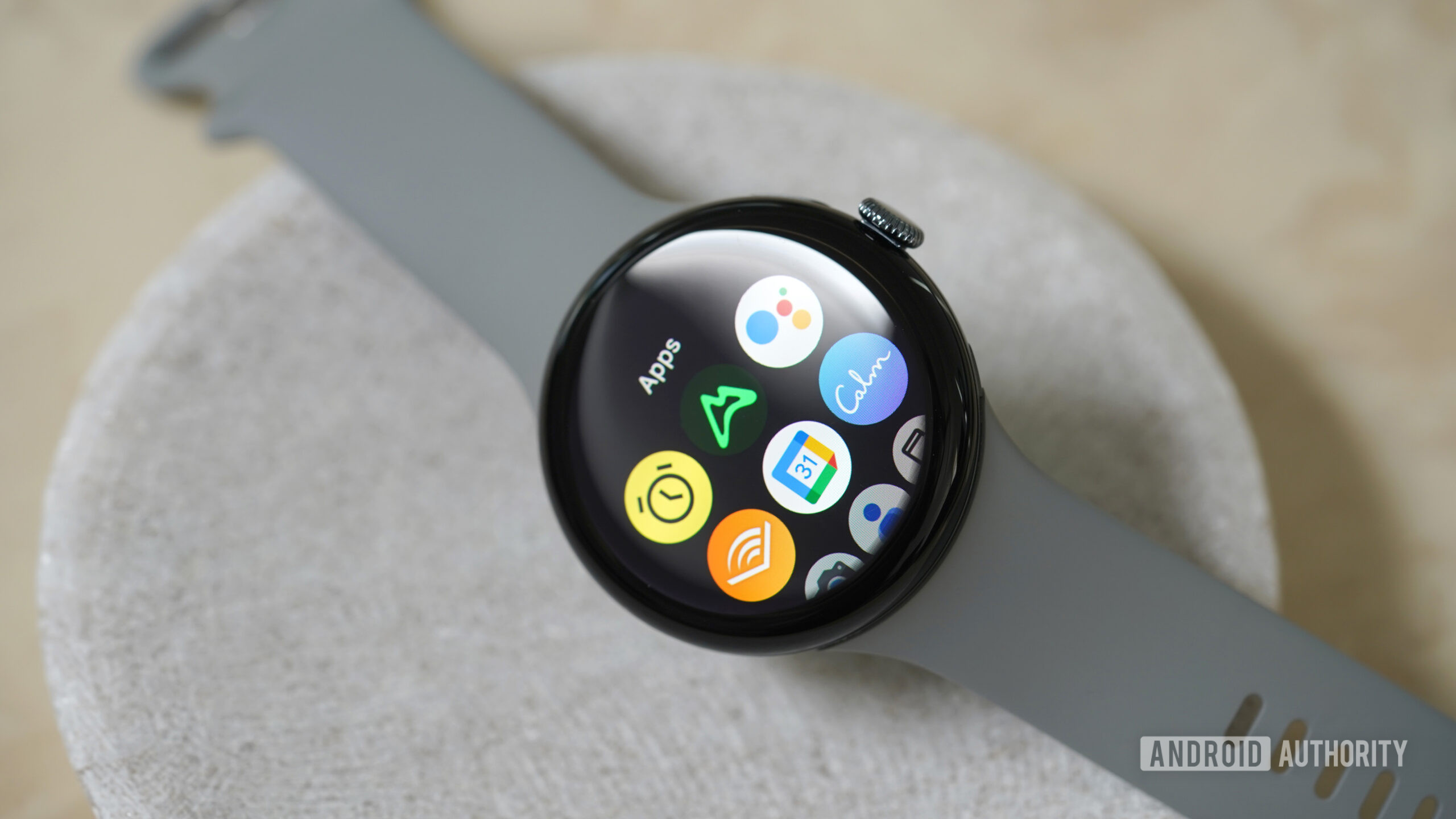 Google Pixel Watch 3 apps A Google Pixel Watch 3 rests on a stone dish, displaying its app library.