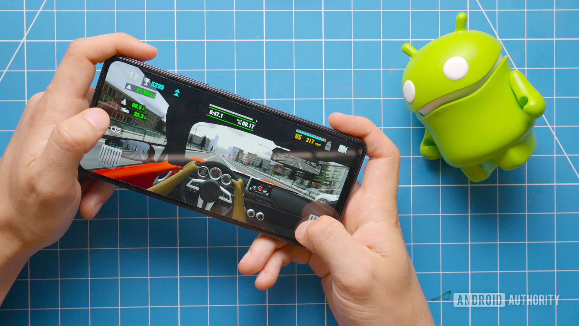 Playing Racing Limits on the Tecno Pova 5 Pro next to Android figure Playing Racing Limits on the Tecno Pova 5 Pro next to Android figure