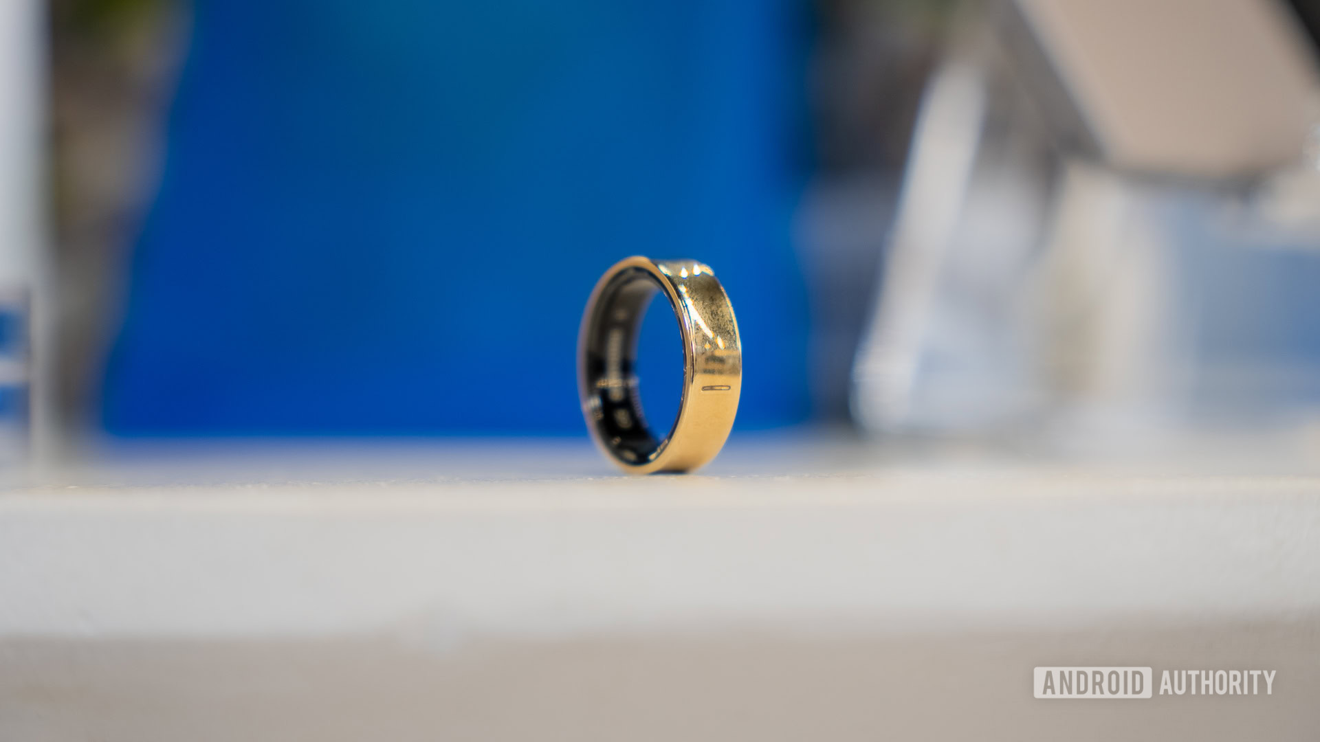 Samsung Galaxy Ring 2 A Gold Titanium Samsung Galaxy Ring rests on a white surface.